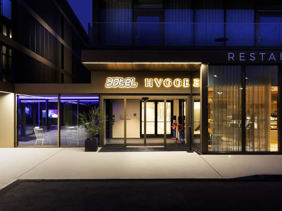 Entrada de un hotel con un cartel que dice 'hotel HVGGE' y un letrero de restaurante arriba.