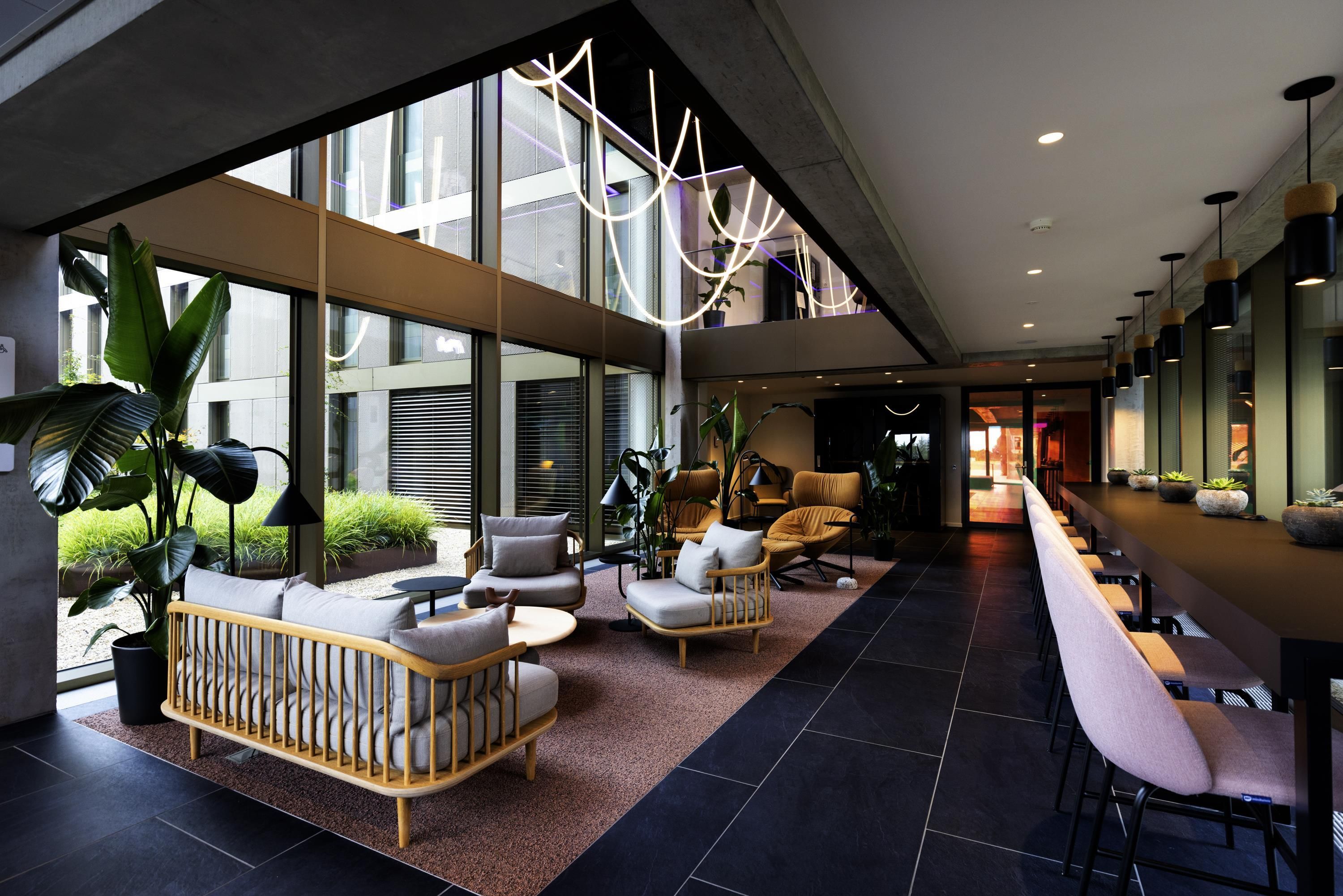 A modern lobby with a seating area, large windows, and a long counter.