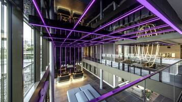 Ein modernes Hotelinterieur mit Glastrennwand, einer Sitzecke und einer neonbeleuchteten Decke.