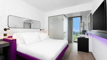 A modern bedroom with a bed, a desk, and a bathroom.