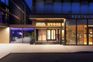 Hotel con restaurante en la planta baja, con fachada moderna, puertas de vidrio y terraza.