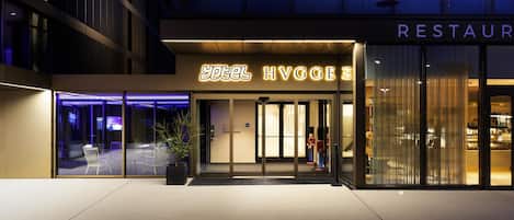 Entrada de un hotel con un cartel que dice 'hotel HVGGE' y un letrero de restaurante arriba.