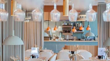 L'intérieur d'un restaurant, avec de nombreuses tables, des chaises et des luminaires suspendus.