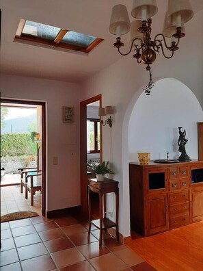 A spacious room with a tiled floor, a wooden cabinet with drawers, a chandelier, and a skylight. - HOLIDAY HOME LA RITANA IN RIBADESELLA (Ribadesella)