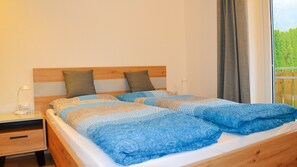 A bed with a wooden headboard, two pillows, and a blue patterned blanket.