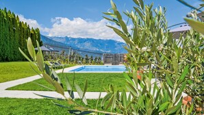 Zona de piscina con vistas a la montaña, rodeada de vegetación y un cielo despejado.