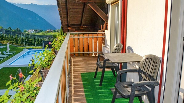 Un balcon avec une piscine, des chaises et une vue sur les montagnes.