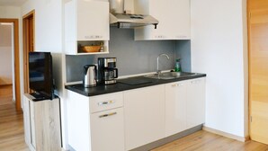 Une cuisine compacte équipée d’une machine à café, d’une bouilloire et d’un évier.