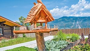 Une nichée à oiseaux en bois, accrochée à un arbre dans un jardin offrant une vue sur la montagne.