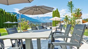 Un espace extérieur aménagé pour les repas, avec des tables, des chaises, des parasols et des plantes en pot.