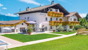 Un bâtiment à deux étages, sur lequel on peut lire l’inscription « Résidence Sannegg ». On y trouve des tables et des chaises à l’extérieur, une pelouse bien entretenue et une clôture en bois.