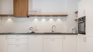 Een moderne keuken met witte kastjes, een roestvrijstalen spoelbak en een inbouwoven.