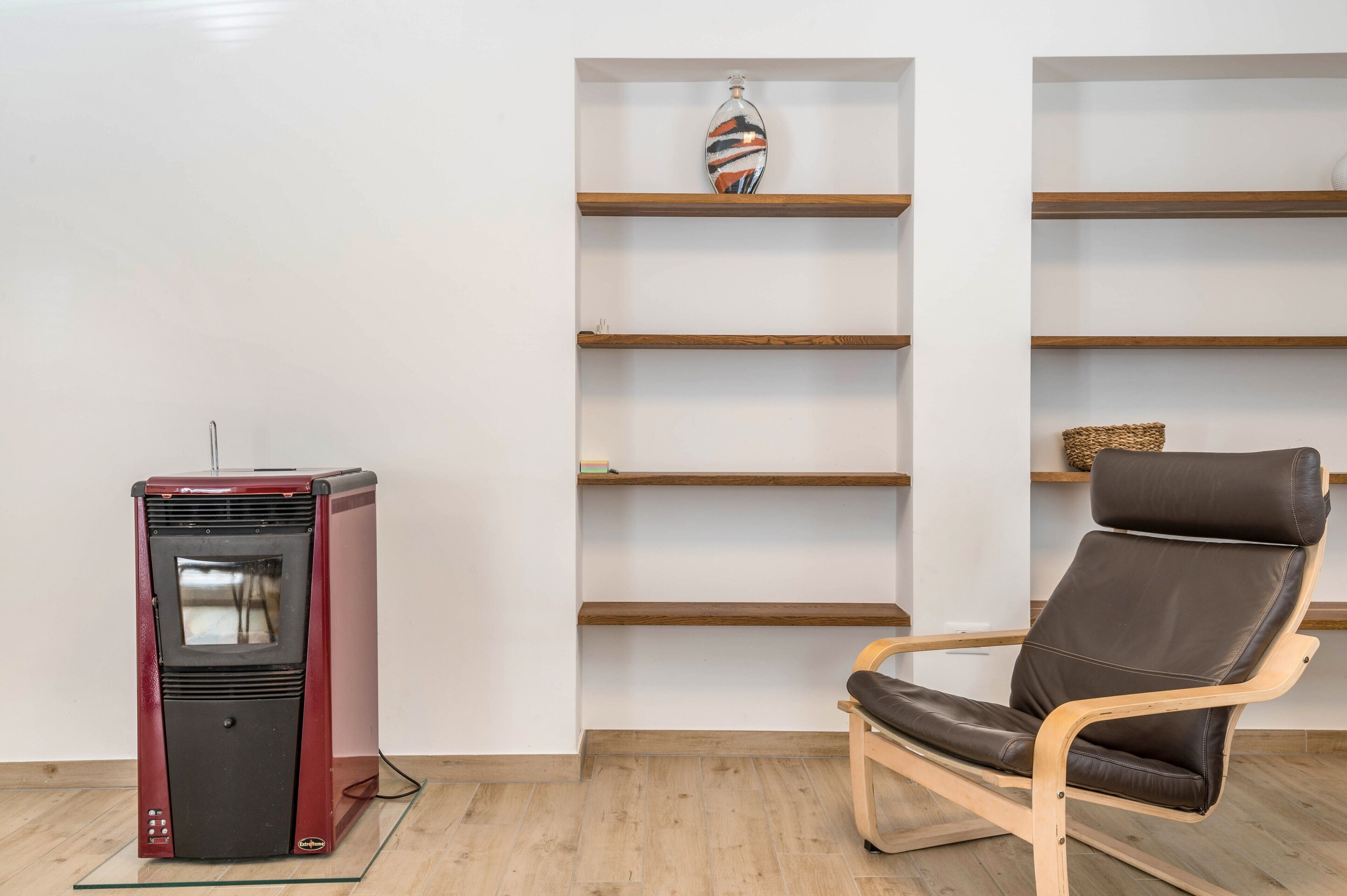 Una habitación con un radiador rojo antiguo, estanterías de madera y un sillón de cuero marrón.