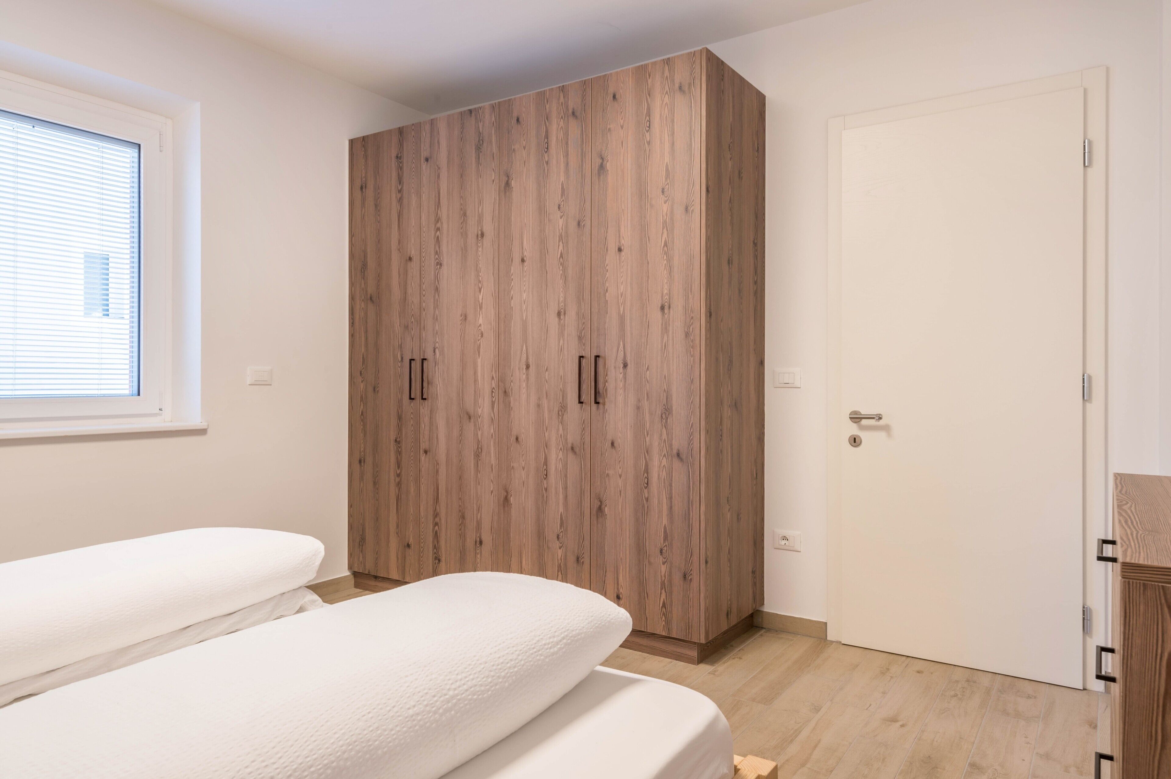 Un dormitorio con un armario grande, una cama y una ventana.