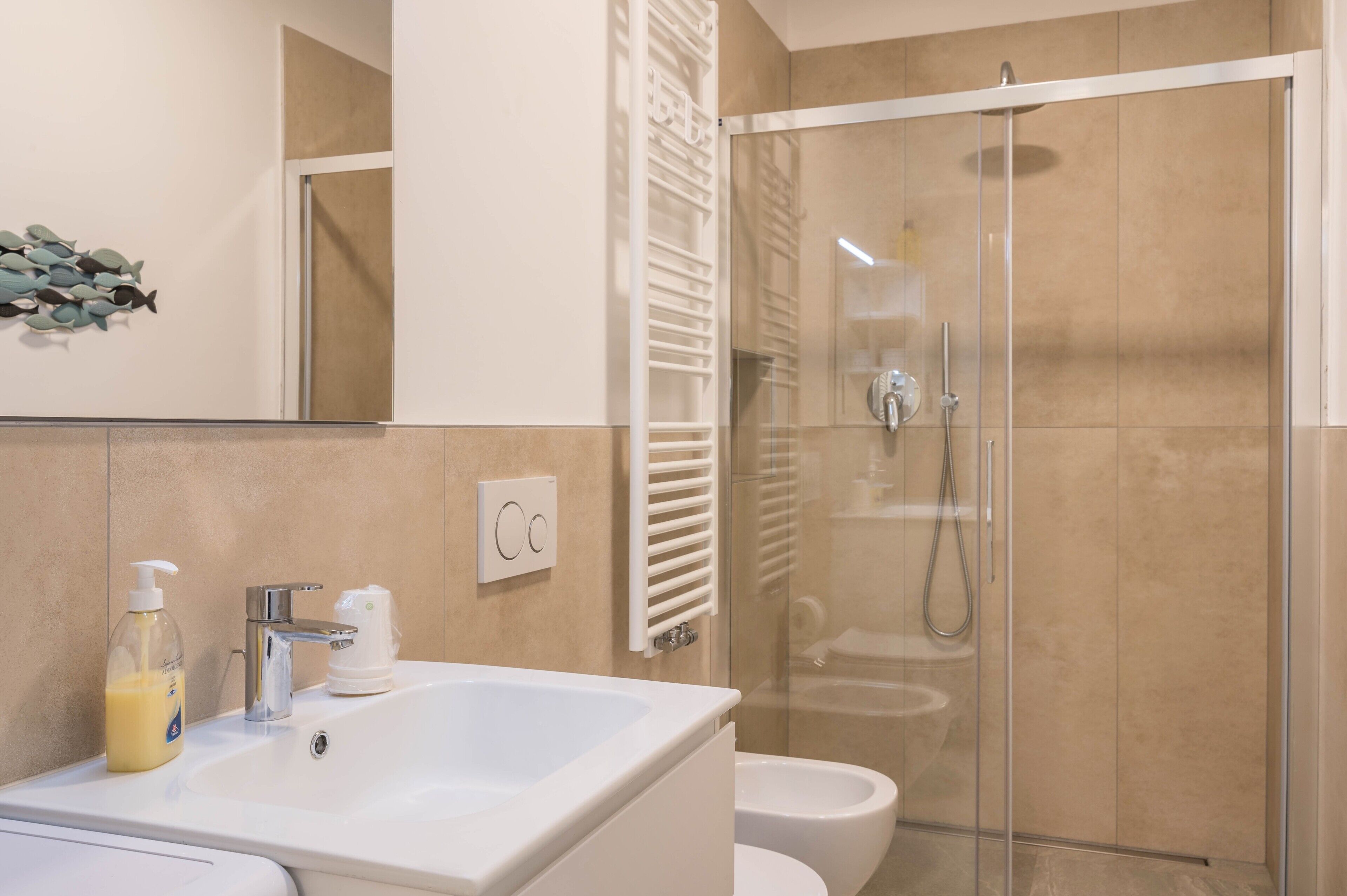 A modern bathroom with a glass-enclosed shower, a white sink, and a toilet.