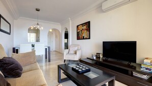 Ein modernes Wohnzimmer mit einer Couch, einem Couchtisch, einem Fernseher und einem Bücherregal.