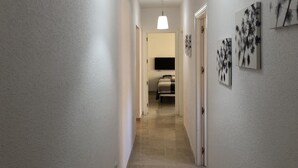 A hallway with a bed, a TV, and wall art. - Holiday Apartment 'Amazing In Puerto Alto' with Sea View, Shared Pool & Wi-Fi (Estepona)