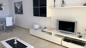 A modern living room with a flat-screen TV, white furniture, and a minimalist design. - Holiday Apartment 'Amazing In Puerto Alto' with Sea View, Shared Pool & Wi-Fi (Estepona)