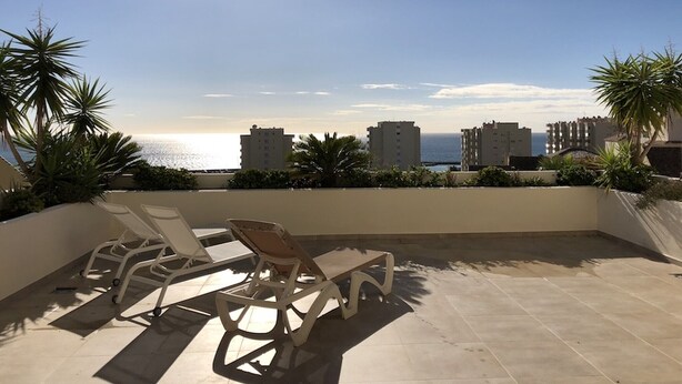 A terrace with two lounge chairs, a view of the sea, and buildings in the background. - Holiday Apartment 'Amazing In Puerto Alto' with Sea View, Shared Pool & Wi-Fi (Estepona)