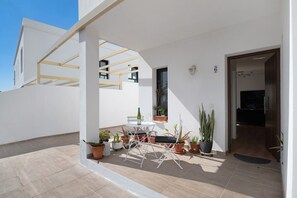Une terrasse extérieure moderne, avec une table et des chaises, entourée de plantes en pot.
