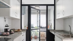 A modern kitchen with a built-in stove, a sink, and a glass door leading to a balcony. - Vacation Home "Gardenia" with Mountain View, Private Terrace & Wi-Fi (Costa Teguise)