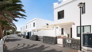 A modern building with a white facade, stone accents, and a covered entrance. - Vacation Home "Gardenia" with Mountain View, Private Terrace & Wi-Fi (Costa Teguise)
