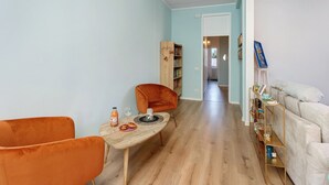 A living room with a wooden coffee table, orange chairs, a bookshelf, and a sofa.