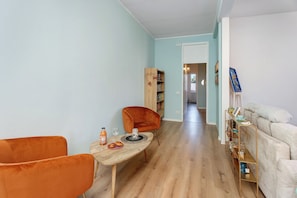 A living room with a wooden coffee table, orange chairs, a bookshelf, and a sofa.