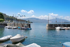 Una marina con imbarcazioni ormeggiate, un molo e montagne sullo sfondo.