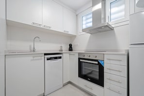 A modern kitchen with white cabinetry, a dishwasher, an oven, and a window above the sink. - Apartment "Formentor 863" with Sea View, Terrace & Wi-Fi (Salou)