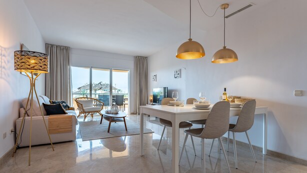 A modern living room with a sofa, dining table, chairs, and a floor lamp.