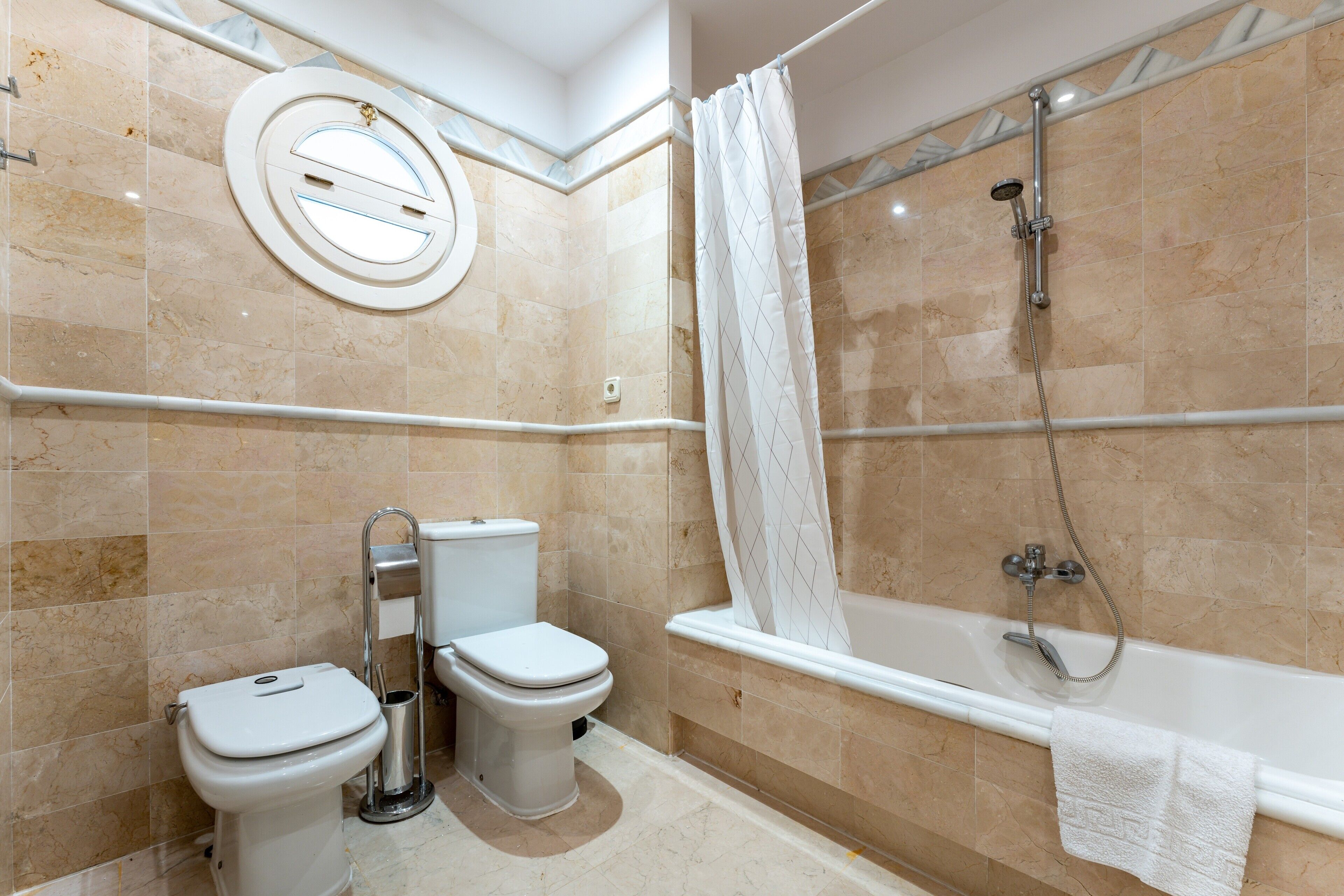 A bathroom with a toilet, bidet, and bathtub.