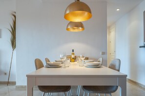 Un comedor con una mesa blanca, seis sillas y dos lámparas colgantes.