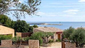 Una propiedad costera con muros de piedra, un edificio pequeño con techo de tejas y vista al mar.