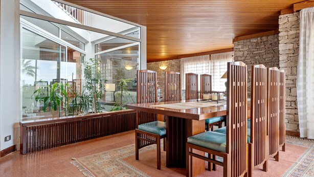 Un comedor moderno con una mesa grande, sillas de madera y vistas al exterior.