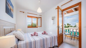Une chambre à coucher avec un lit, une lampe de chevet et une vue sur une terrasse extérieure.