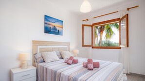 Une chambre à coucher avec un lit, des tables de chevet, une lampe, un tableau et une fenêtre avec des rideaux.