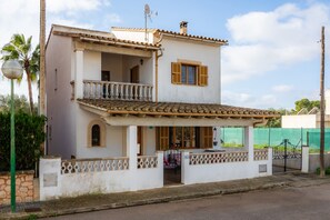 Une maison à deux étages avec un balcon, une véranda et une cour clôturée.