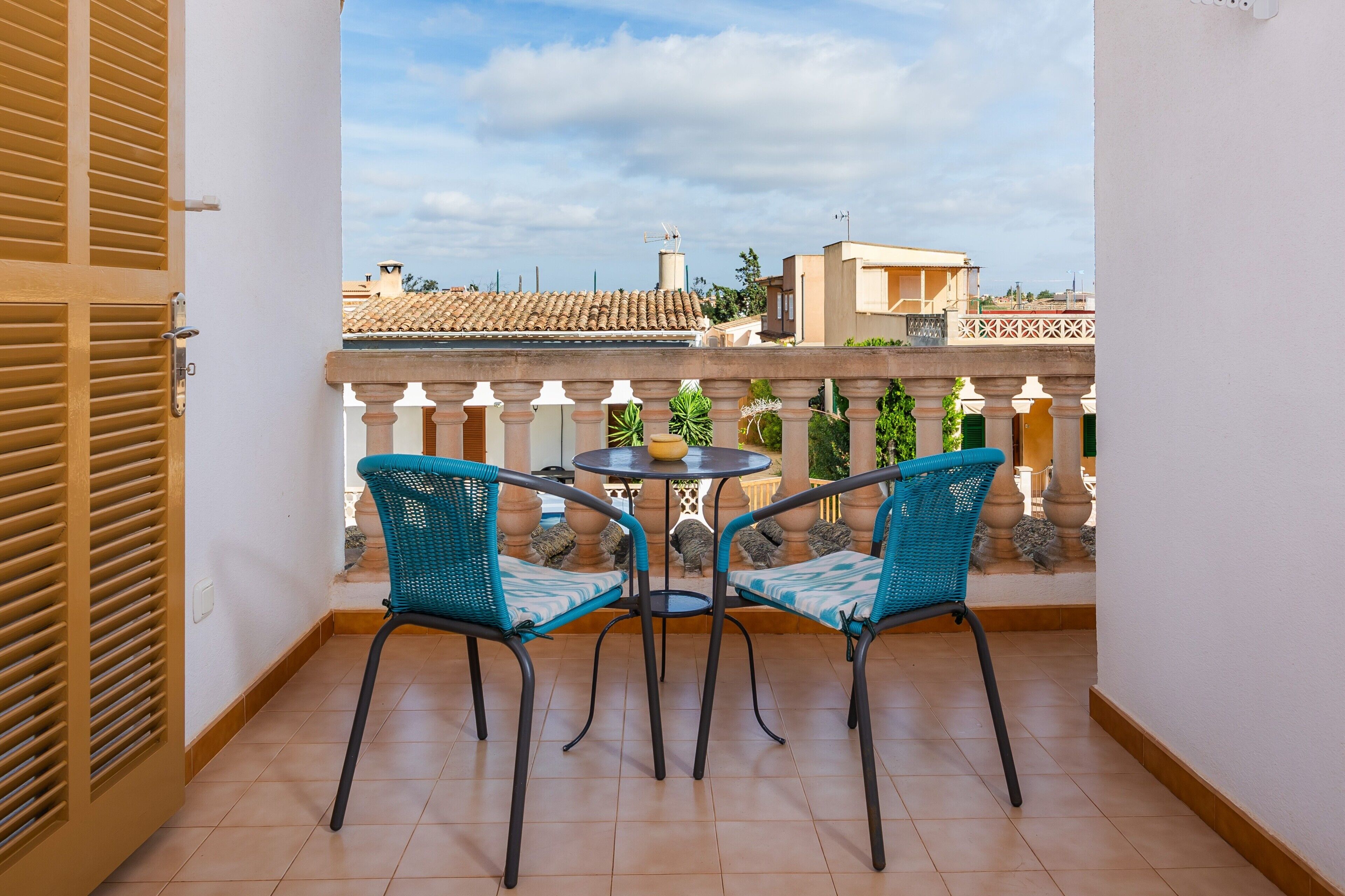 Een balkon met twee stoelen en een kleine tafel, met uitzicht op een stadsbeeld.