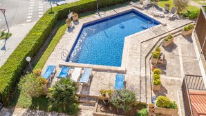 A swimming pool with lounge chairs, surrounded by planters and a well-maintained hedge. - Holiday Home 'Apt Con Piscina Y Jardín' with Shared Pool, Wi-Fi and Air Conditioning (Puerto Pollensa)