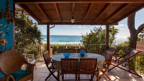 A covered patio with a round table and chairs, overlooking the ocean. - Vacation Home Casa sulla Spiaggia 1 with Sea-View, Terraces & Garden (Orosei)