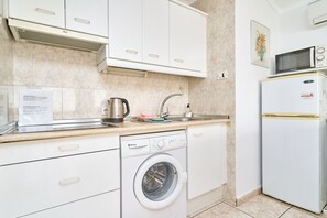 A compact kitchen with a built-in washing machine, a microwave, and a sink.