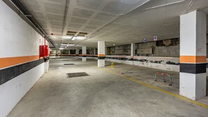 A parking garage with concrete floors, white and orange walls, and visible structural columns. - Apartment 'Diseño A Pie De Pista' with Mountain View and Wi-Fi (Monachil)
