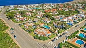 Vista aérea de una zona residencial costera con casas, carreteras y un mar azul cristalino.