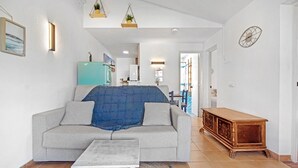 Una sala de estar con un sofá, una mesa de centro, un mueble de madera y un reloj de pared.