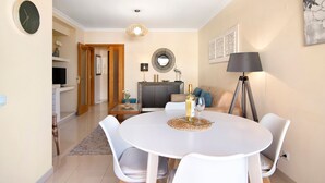 A dining area with a round table, chairs, a lamp, and a bottle of wine.