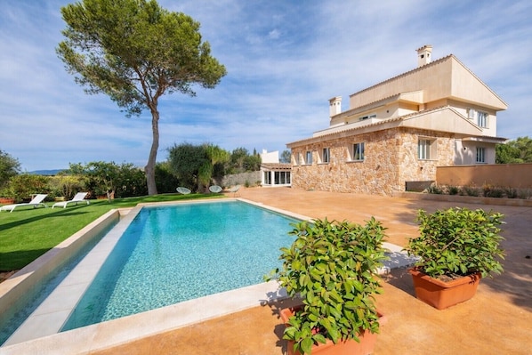 A pool with a stone house in the background.
