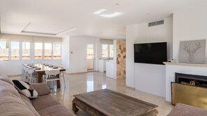 A spacious living area with a sofa, coffee table, TV, fireplace, and dining area.