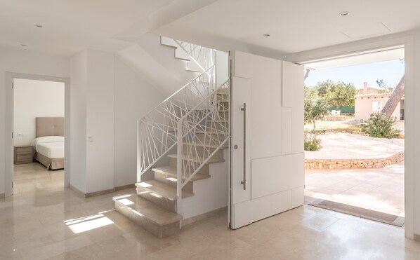 A modern interior with a staircase, a bed, and a view of the outside. - Villa Can Luciana with Private Pool, Garden, and Exclusive Outdoor Area in Mallorca (S'Aranjassa)