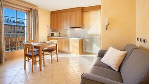 A compact living space with a dining area, kitchenette, and a sofa with a cushion.
